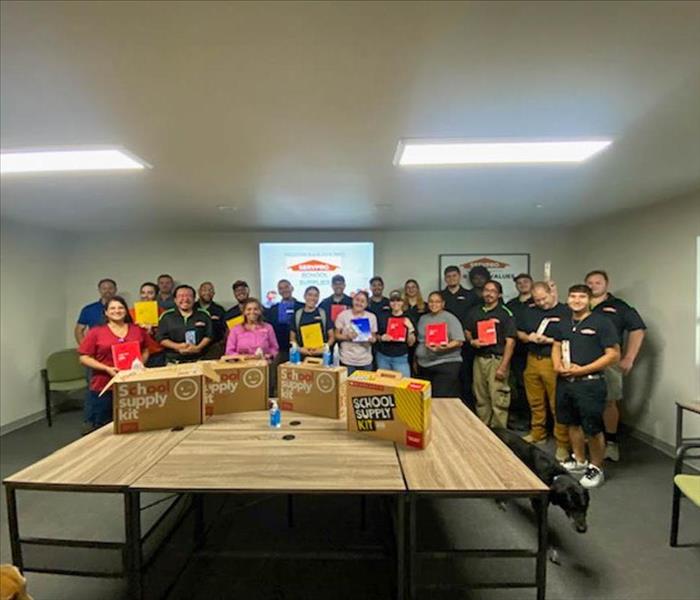 SERVPRO team standing together with school supplies